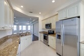 Located at 4427 Kings Barn Ct in Fort Myers, Florida, this well-appointed single-floor residence offers a thoughtfully designed layout with three bedrooms, three bathrooms, and a generous overall footprint. The open-concept kitchen serves as a central hub, featuring cream-toned cabinetry with raised-panel detailing, granite countertops, stainless steel appliances including a refrigerator, range, and dishwasher, and light tile flooring that flows seamlessly into the dining area. A curved tray ceiling distinguishes the living room, which is accented by recessed lighting, rich hardwood-style flooring, and a bay window arrangement that fills the space with natural light.

The spacious primary bedroom includes a walk-in closet with built-in wire shelving and direct access to a private en-suite bathroom. The primary bath features a granite-topped vanity, a soaking tub surrounded by tile surround, a separate shower, and louvered bi-fold closet doors. Additional bedrooms also feature hardwood-style flooring and access to their own closets.

A standout feature is the screened balcony, which offers panoramic views of a tranquil lake and tree canopy, providing a serene outdoor retreat. Throughout the residence, neutral tones and consistent finishes create a cohesive, refined ambiance.