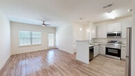Located at 40 Cohen Walker Dr in Warner Robins, GA, this single-story 2-bedroom, 1-bathroom home offers a well-designed, open-concept layout finished with warm wood-look flooring throughout. The living area is bright and welcoming, filled with natural light from large windows and equipped with a ceiling fan overhead. It flows seamlessly into the kitchen, which features white shaker-style cabinetry, granite countertops, stainless steel appliances including a range, microwave, and dishwasher, a deep single-basin sink, and pendant lighting above a peninsula island — ideal for both cooking and casual dining. A dedicated hallway connects the living spaces to the two bedrooms. The spacious primary bedroom offers a generous walk-in closet with wire shelving, while the second bedroom includes a double-door closet and a window with outdoor views. The full bathroom is outfitted with granite countertops, an undermount sink, and a tub-shower combination. Additional features include track lighting at the entry, an attached garage with an automatic opener and a concrete floor, providing practical storage and parking space.