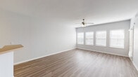 This single-floor space is designed with a clean, neutral aesthetic that creates a bright and open atmosphere throughout. The main living area is spacious and features wood-look laminate flooring, white walls, and a ceiling fan with a light fixture. Multiple windows fitted with horizontal blinds allow natural light to fill the room, while a door provides access to an exterior area. A half-wall partition with a warm-toned countertop separates the living area from the kitchen, adding a subtle architectural detail.

The kitchen is efficiently laid out with white cabinetry, warm countertops, and tile flooring. It is equipped with a full suite of white appliances, including a refrigerator, electric range, over-the-range microwave, and dishwasher, along with ample cabinet storage.

The bedrooms are carpeted for comfort and each includes a ceiling fan, neutral-toned walls, and a window that brings in natural light. A hallway connects the bedrooms to the rest of the unit.

The bathrooms feature tile flooring, white vanity cabinetry with warm countertops, a wall-mounted mirror, and a tub/shower combination enclosed by sliding glass doors, maintaining the unit's consistent, functional design throughout.