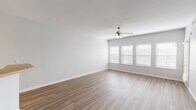 This single-floor space is designed with a clean, neutral aesthetic that creates a bright and open atmosphere throughout. The main living area is spacious and features wood-look laminate flooring, white walls, and a ceiling fan with a light fixture. Multiple windows fitted with horizontal blinds allow natural light to fill the room, while a door provides access to an exterior area. A half-wall partition with a warm-toned countertop separates the living area from the kitchen, adding a subtle architectural detail.

The kitchen is efficiently laid out with white cabinetry, warm countertops, and tile flooring. It is equipped with a full suite of white appliances, including a refrigerator, electric range, over-the-range microwave, and dishwasher, along with ample cabinet storage.

The bedrooms are carpeted for comfort and each includes a ceiling fan, neutral-toned walls, and a window that brings in natural light. A hallway connects the bedrooms to the rest of the unit.

The bathrooms feature tile flooring, white vanity cabinetry with warm countertops, a wall-mounted mirror, and a tub/shower combination enclosed by sliding glass doors, maintaining the unit's consistent, functional design throughout.