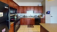 This single-floor residence in Oshkosh, Wisconsin offers a thoughtfully designed layout across several functional living spaces. The kitchen is a standout feature, showcasing rich cherry wood cabinetry, dark granite-style countertops, tile flooring, and black appliances including a range and dishwasher. A central island with seating and a pendant light fixture above adds both style and practicality to the space.

The living area is carpeted and features a ceiling fan, a sliding glass door that opens to a balcony with open exterior views, and ample room for seating and entertainment. An additional secondary sitting room provides extra flexible living space, also carpeted and ceiling fan-equipped.

The bedrooms are carpeted and well-proportioned, each with ceiling fans and windows that bring in natural light. One bedroom includes a dedicated study area with a hutch desk and shelving, while another features a closet and cozy reading nook. Both bathrooms are finished with tile flooring, cherry wood vanities, and granite-style countertops. One bathroom includes a tub and shower combination, while the other features a single vanity with mirror and updated fixtures throughout.

The overall layout is practical and comfortable, with consistent warm-toned finishes connecting each room cohesively.