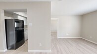 This 1-bedroom, 1-bathroom single-floor unit offers a thoughtfully laid-out living space with a clean, neutral aesthetic. Light wood-style flooring runs consistently throughout, complementing the warm beige tones on the walls and bright white trim. The open living area provides a welcoming entry point, with ample room for furnishings and access to the adjacent kitchen. The kitchen is efficiently designed, featuring black appliances including a full-size refrigerator and an electric range, white cabinetry, and a skylight that introduces natural light overhead. A partial wall divides the kitchen and living areas, maintaining an open feel while defining each space. The bedroom is a comfortable, well-proportioned room with a ceiling fan, a window offering natural light and outdoor views, and direct access to a walk-in closet equipped with dual hanging rods and shelving on multiple walls. The bathroom includes a full tub-shower combo with white tile surround, a small window for ventilation, and a textured ceiling. Throughout the unit, the consistent flooring, neutral palette, and clean finishes create a cohesive and move-in ready environment.