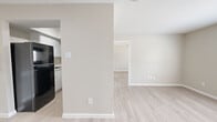 This 1-bedroom, 1-bathroom single-floor unit offers a thoughtfully laid-out living space with a clean, neutral aesthetic. Light wood-style flooring runs consistently throughout, complementing the warm beige tones on the walls and bright white trim. The open living area provides a welcoming entry point, with ample room for furnishings and access to the adjacent kitchen. The kitchen is efficiently designed, featuring black appliances including a full-size refrigerator and an electric range, white cabinetry, and a skylight that introduces natural light overhead. A partial wall divides the kitchen and living areas, maintaining an open feel while defining each space. The bedroom is a comfortable, well-proportioned room with a ceiling fan, a window offering natural light and outdoor views, and direct access to a walk-in closet equipped with dual hanging rods and shelving on multiple walls. The bathroom includes a full tub-shower combo with white tile surround, a small window for ventilation, and a textured ceiling. Throughout the unit, the consistent flooring, neutral palette, and clean finishes create a cohesive and move-in ready environment.