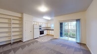 This single-floor residential unit offers a practical and well-organized layout designed for comfortable everyday living. The open-concept main living area seamlessly connects to the kitchen, creating a spacious, unified space. Soft carpet flooring flows throughout the living area, while the kitchen transitions to durable tile flooring. A sliding glass door opens directly onto a private balcony, bringing in natural light and offering views of the surrounding outdoor environment.

The kitchen is efficiently designed in an L-shaped configuration, featuring white cabinetry with light wood trim, dark laminate countertops, a stainless steel sink, and a full suite of white appliances including a refrigerator, electric range, built-in microwave, and dishwasher. A window above the sink allows additional natural light into the space.

Adjacent to the living area, built-in open shelving provides convenient display and storage options, while a closet offers additional enclosed storage. The entry area is bright and welcoming, with access to a walk-in closet and a wall-mounted heating unit.

The bathroom includes a wide vanity with a laminate countertop and light wood cabinetry, a large mirror, a shower/tub combination, and tile flooring, providing a clean and functional space. Textured ceilings are present throughout, adding a classic residential finish to the unit overall.