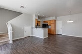 Located at 8250 Vineyard Ave in Rancho Cucamonga, CA, this two-story home offers a well-organized layout with functional living spaces across both levels. The main floor features an open-concept design where the kitchen flows seamlessly into the living and dining areas. The kitchen is equipped with warm honey-toned wood cabinetry, granite-style countertops, a peninsula with a double sink, and a full suite of black appliances including a gas range, built-in microwave, dishwasher, and refrigerator. Recessed lighting and vaulted ceiling details above the kitchen add a sense of openness and brightness. Light wood-look flooring runs throughout the main living areas, complementing the neutral wall tones. A pendant light fixture anchors the dining area, which benefits from natural light through a sliding door. The staircase leads to the upper level, where carpeted bedrooms provide comfort and quiet. Each bedroom features neutral walls, blinds, and windows that allow natural light and outdoor views. Bathrooms are finished consistently with wood-look flooring, wood-toned vanity cabinetry, granite-style countertops, and tub-shower combinations. The overall aesthetic is clean, cohesive, and move-in ready, making this Rancho Cucamonga home a practical and comfortable residence.