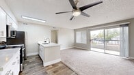 Located at 10 E Bell Rd in Phoenix, AZ, this one-bedroom, one-bathroom unit offers a well-designed open-concept layout that seamlessly connects the kitchen and living area. The kitchen is outfitted with crisp white shaker cabinets, quartz countertops, stainless steel appliances including a range, over-the-range microwave, and refrigerator, and a peninsula with a sink that opens to the living space. Wood-look plank flooring anchors the kitchen area, transitioning to plush carpet throughout the living room and bedroom. The spacious living room is bathed in natural light from a large window and sliding glass door that leads to a private balcony, offering outdoor views. A ceiling fan provides additional comfort. The generously sized primary bedroom features a large window with blinds, carpeted floors, and direct access to a closet. The bathroom includes a white vanity with quartz countertops, ample cabinetry, and a full shower/tub combo, with wood-look flooring tying the space together. A hallway connects the rooms efficiently, and in-unit laundry hookups are present. Neutral tones and clean finishes give the space a modern, move-in-ready feel.