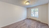 Located at 2128 62nd Ave E in Fife, Washington, this two-bedroom, one-bathroom single-story home offers a functional and comfortable layout. The open-concept living and dining area serves as the heart of the home, featuring a combination of tile and carpet flooring beneath a textured ceiling. Natural light filters in through the windows, creating a bright and welcoming atmosphere. The space flows directly into a galley-style kitchen, which is equipped with warm wood-toned cabinetry, ample upper and lower storage, a double sink with countertop workspace, and white appliances including an electric range and refrigerator. Tile flooring runs throughout the kitchen for easy maintenance. Both bedrooms are carpeted and generously sized, each featuring a window that brings in natural light and is outfitted with baseboard heating. The bedrooms are served by multiple closets, providing excellent storage throughout. A shared full bathroom includes a single vanity with a large mirror, a toilet, and a tub/shower combination, all finished with tile flooring. A utility room and hallway complete the practical layout of this well-organized home, rounding out a straightforward and livable single-floor floor plan.