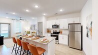This 1-bedroom, 1-bathroom unit in Baton Rouge, Louisiana, offers a thoughtfully designed open-concept layout with modern finishes throughout. The kitchen serves as a focal point of the living space, featuring crisp white shaker cabinetry, granite countertops, a subway tile backsplash, and stainless steel appliances including a range, microwave, and refrigerator. A peninsula island with bar seating provides additional dining and prep space, flowing seamlessly into the living area. The living room is bright and welcoming, with recessed lighting, a ceiling fan, light wood-style flooring, and a glass door that brings in natural light and outdoor access. The bedroom offers a comfortable, well-proportioned space with a ceiling fan, a large window with natural light, and a carpeted floor. The bathroom features granite countertops, white cabinetry, a large mirror, and direct access to a dedicated closet with built-in shelving and hanging rods. Light wood-style flooring carries through the main areas, complementing the clean, neutral color palette. The overall ambiance is modern and cohesive, with consistent design elements that make efficient use of the available space.
