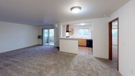 Located at 4034 Idlewild Loop in Coeur d'Alene, Idaho, this single-floor unit offers a practical and comfortable layout designed for everyday living. The open living area is finished with plush carpet and receives natural light through a sliding glass door that leads to a private balcony, providing pleasant outdoor views of the surrounding landscape.

The kitchen is connected to the living space via a pass-through counter opening, creating an accessible and functional flow between rooms. It is equipped with warm-toned wood cabinetry offering generous upper and lower storage, light-colored countertops, a double stainless steel sink, and black appliances including a refrigerator and dishwasher. A window above the sink frames scenic views of the treeline and hills beyond.

The bedrooms are carpeted and well-proportioned, each featuring sliding wood closet doors with built-in shelving and hanging rods. The neutral wall tones throughout keep the spaces feeling bright and versatile.

Two bathrooms serve the unit, both finished with wood-look flooring and warm wood cabinetry. One bathroom features a full tub and shower combination with chrome fixtures, while the other offers a vanity with a wide mirror and a high placement window for natural light. The overall design is clean and functional, making this a well-appointed space in a scenic Idaho setting.