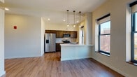 Located at 156 S Main St in the heart of downtown Akron, Ohio, this single-floor unit offers a thoughtfully designed open-concept layout finished with consistent wood-look flooring throughout the living areas. The spacious living area is anchored by large windows fitted with roller shades, allowing abundant natural light to pour in while framing views of the surrounding urban streetscape.

The kitchen is a standout feature, equipped with stainless steel appliances including a refrigerator with ice and water dispenser, electric range, microwave, and dishwasher. Rich dark-stained cabinetry is complemented by a classic subway tile backsplash and light quartz countertops. A peninsula with an undermount sink and pendant lighting overhead creates a natural divider between the kitchen and living area, offering additional workspace and casual seating.

The bathroom is finished to a high standard, featuring large-format neutral tile flooring, a tiled walk-in shower with sliding glass doors, a dark wood vanity with quartz countertop, an undermount sink, and a backlit mirror that adds a contemporary touch. Recessed lighting throughout the unit contributes to the clean, modern aesthetic of this well-appointed downtown Akron residence.