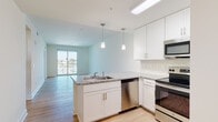 Located at 16520 San Carlos Blvd in Fort Myers, FL, this single-floor residence offers a clean, modern aesthetic throughout its open and well-appointed layout. Light hardwood flooring flows consistently across the living spaces, complementing the bright white walls and creating a cohesive, airy atmosphere.

The kitchen is a standout feature, designed with white shaker cabinetry, granite countertops, and a peninsula with an undermount sink and built-in dishwasher. Stainless steel appliances — including a refrigerator, range, and microwave — are complemented by stylish pendant lighting and a white subway tile backsplash, making the space both functional and visually appealing. The kitchen opens directly into the living area, which benefits from natural light and direct access to a private balcony overlooking palm-lined surroundings.

The bedrooms are generously proportioned, featuring tray ceilings, ceiling fans, and large windows that frame pleasant outdoor views of the Fort Myers landscape. Each bathroom is finished with granite countertops, white cabinetry, undermount sinks, and white subway tile shower surrounds, maintaining a consistent, polished design language throughout. The overall ambiance of this residence is bright, contemporary, and move-in ready, reflecting quality finishes in a desirable Southwest Florida location.