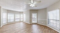 This thoughtfully designed one-bedroom, one-bathroom unit features a single-floor layout that maximizes functionality and comfort throughout. The combined kitchen and living room serves as the heart of the space, where a generous bay window arrangement floods the area with natural light and creates an inviting, open atmosphere. The living area is equipped with a ceiling fan and light fixture, complemented by wood-look plank flooring that extends throughout the unit. A textured ceiling adds subtle character overhead, while neutral gray walls provide a clean, versatile backdrop.

The kitchen is laid out in a galley-style configuration, offering white cabinetry, white countertops, a double-basin stainless steel sink, and black appliances including a refrigerator, electric range, and dishwasher. A pass-through window connects the kitchen to the living area, enhancing the open feel. The kitchen also provides access to a hallway and closet for added storage.

The bedroom is a comfortable, well-proportioned room with its own ceiling fan, a window for natural light, and direct access to a dedicated closet with built-in shelving. The full bathroom includes a tub-shower combination with grab bars, a vanity with white cabinetry, a medicine cabinet, and wood-look flooring, completing this efficiently organized and move-in-ready unit.