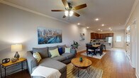 Located in Tontitown, Arkansas, this two-story home offers a thoughtfully designed layout across two levels. The main floor showcases an open-concept living and dining area with warm hardwood flooring, crown molding, and ceiling fans with integrated lighting. Recessed lighting throughout enhances the bright, welcoming ambiance. The living room provides ample space for relaxing, with a front entry door and window that invite natural light. Flowing seamlessly into the dining area, the space connects directly to the kitchen, which features rich cherry wood cabinetry, granite countertops, a large kitchen island with bar seating, stainless steel appliances, and tile flooring. A staircase visible from the kitchen leads to the upper level. The bedrooms are carpeted for comfort, each equipped with ceiling fans, and offer generous space for furnishings. One bedroom features a large window with outdoor views and natural light. The bathrooms are finished with tile flooring, wood vanities with granite countertops, and well-lit mirrors, delivering a clean and functional aesthetic throughout. The consistent use of quality materials — from the granite surfaces to the stainless appliances and hardwood floors — gives this Tontitown home a cohesive, polished character.