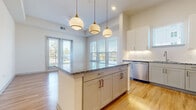 Located in Northlake, TX, this single-story 4-bedroom, 2-bathroom home offers a well-designed layout with modern finishes throughout. The open-concept kitchen and living area serves as the heart of the home, featuring white shaker cabinetry, granite countertops, a subway tile backsplash, and a full suite of stainless steel appliances including a refrigerator, range, microwave, and dishwasher. A central kitchen island with pendant lighting adds both function and style, while large windows and a set of glass doors flood the living space with natural light and provide outdoor views. Light hardwood flooring runs throughout the main living areas, lending a warm and cohesive feel. The four bedrooms are comfortably sized, with the primary bedroom offering generous proportions, plush carpeting, and access to a well-organized walk-in closet complete with built-in shelving and hanging rods. Additional bedrooms also feature carpet flooring and large windows that bring in ample natural light. The two bathrooms are finished with granite vanity countertops, wood-look tile flooring, and a tiled tub-shower surround with brushed nickel fixtures. Multiple hallways and two closets round out the practical and efficiently arranged floor plan of this Northlake residence.