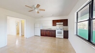 Located at 8570 W Mayo Dr in Crystal River, Florida, this single-story, one-bedroom, one-bathroom unit offers a practical and functional layout across a compact footprint. Light-toned ceramic tile flooring runs throughout the entire space, contributing to a clean, cohesive look and easy maintenance.

The open-concept living and kitchen area forms the heart of the unit. The kitchen is equipped with rich, dark-stained wood cabinetry — both upper and lower — paired with light countertops, a single-basin sink, a white electric range with an overhead ventilation hood, and a full-size refrigerator. A tile backsplash adds a subtle design detail behind the cooking area. A ceiling fan with light fixture overhead provides air circulation, while a large picture window frames outdoor views of the surrounding greenery and open landscape, allowing natural light to fill the space.

The bedroom is a well-proportioned room bathed in natural light, with clean white walls and the same tile flooring. A dedicated closet provides convenient storage. The bathroom includes a full-size bathtub and shower combination with white tile surround, a toilet, and a window that provides natural ventilation and light. The textured ceilings are consistent throughout the unit, adding a familiar Florida residential character to the overall interior.
