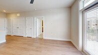 Located at 15506 Interplace Rd in San Antonio, TX, this thoughtfully designed 2-bedroom, 2-bathroom residence offers a clean, modern aesthetic throughout its single-floor layout. The open-concept kitchen and living area serves as the heart of the home, featuring grey shaker-style cabinetry, a decorative white geometric tile backsplash, stainless steel appliances, and a central island with quartz countertops, an undermount sink, and pendant lighting overhead. Light wood-style flooring flows throughout the main living areas, adding warmth and continuity. The living room is bright and airy, with a ceiling fan and French doors topped by a transom window that open to a private balcony, inviting natural light and outdoor views. The spacious primary bedroom features plush carpeting, a ceiling fan, a large window with outdoor views, and access to an en suite bathroom. The primary bath is finished with wood-look flooring, an extended vanity with gold hardware, wall-mounted cabinetry, and a walk-in closet. The second bedroom also features soft carpeting, a ceiling fan, and a double-door closet. The secondary bathroom includes a tiled tub-shower combination, grey cabinetry, and brushed nickel fixtures. Neutral tones and clean lines throughout lend the space a cohesive, contemporary feel.
