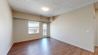 Located at 17821 Cypress Dr in Omaha, Nebraska, this 1-bedroom, 1-bathroom unit offers a thoughtfully designed single-floor layout that maximizes every square foot. The open-concept kitchen and living area forms the heart of the home, where warm wood-look flooring flows throughout. The kitchen is outfitted with grey shaker-style cabinetry, granite-look countertops, a white subway tile backsplash, stainless steel appliances — including a refrigerator, electric range, and built-in microwave — and a peninsula with a double-basin sink featuring a matte black faucet. The living area is bright and airy, benefiting from natural light and direct access to a private balcony through a glass door. The bedroom is carpeted for comfort, features a ceiling fan, a generous window with neighborhood views, and is accompanied by a dedicated closet for ample storage. The bathroom is clean and modern, with wood-look flooring, a walk-in shower with white surround, and matte black hardware and fixtures throughout. Neutral wall tones and consistent finishes create a cohesive and move-in-ready atmosphere across the entire space.