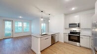 Located at 1700 Ranch Rd. in Nokomis, Florida, this well-appointed 2-bedroom, 3-bathroom residence offers a thoughtfully designed single-floor layout with modern finishes throughout. The open-concept kitchen serves as the heart of the home, featuring a central island with a granite countertop, undermount sink, and elegant pendant lighting. White flat-front cabinetry, a subway tile backsplash, and a full suite of stainless steel appliances — including a range, microwave, dishwasher, and refrigerator — complete the space with a clean, contemporary aesthetic. Warm-toned luxury vinyl plank flooring flows through the main living areas, creating a cohesive and inviting atmosphere. Natural light pours in through multiple windows fitted with blinds. The primary bedroom includes direct access to a well-sized walk-in closet with wire shelving and an en-suite bathroom featuring granite countertops, a large mirror, and a soaking tub alongside subway-tiled walls. A separate glass-enclosed walk-in shower is found in another bathroom, maintaining the home's consistent modern style. The secondary bedroom is carpeted, bright, and includes a ceiling fan. Two closets provide ample storage throughout the residence. The overall design balances clean lines with functional living in a comfortable Florida setting.