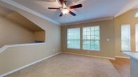 This single-floor, 2-bedroom, 2-bathroom residence combines practical design with comfortable living spaces. The living room serves as the heart of the home, featuring plush carpeting, crown molding, a ceiling fan, and multiple windows dressed with blinds that frame views of lush greenery. A distinctive built-in niche adds character to the space, while an arched transom window near the kitchen pass-through brings in additional natural light.

The kitchen is efficiently designed with light wood cabinetry, white appliances including a refrigerator, electric range, and over-the-range microwave, complemented by wood-look flooring and clean white countertops.

Both bedrooms are generously sized, each featuring soft carpeting, ceiling fans, and windows that invite natural light. The primary bedroom is accompanied by an en-suite bathroom boasting a dual-sink vanity with light wood cabinetry, a large mirror with overhead lighting, and access to a spacious walk-in closet with built-in shelving and hanging rods. The second bathroom offers a tiled tub-and-shower combination with wood-look flooring. Throughout the residence, warm beige tones create a cohesive and inviting ambiance.
