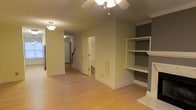 Located at 100 Adelaide Cir in Morrisville, NC, this two-story home offers a well-designed layout that balances comfort and functionality. The main level features warm hardwood-style flooring that extends throughout the open living areas, creating a cohesive and inviting atmosphere. A standout feature of the living room is the built-in shelving unit flanking a classic fireplace with a marble-style surround, providing both aesthetic appeal and practical storage. Crown molding along the ceilings adds a refined architectural touch throughout the space. A ceiling fan with light fixture ensures year-round comfort in the main living area. The hallway leading from the living space offers a clear sightline through the home, with access to additional rooms and a staircase that connects to the second floor. The staircase, visible from the main corridor, features traditional white balusters and a wooden railing, contributing to the home's classic design aesthetic. Natural light filters through the space, complementing the neutral wall tones and light-colored trim. The home's interior presents a clean, move-in-ready condition with a timeless color palette that provides a versatile backdrop for a variety of furnishing styles.