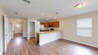 Located at 9872 Trout Tides Blvd in Jacksonville, FL, this two-story home offers five bedrooms and three bathrooms across two well-proportioned floors. The main level features an open-concept kitchen and living area anchored by a granite-topped island with a built-in sink, warm wood cabinetry, stainless steel appliances, and recessed lighting. A walk-in pantry adds practical storage, and wood-look flooring flows seamlessly throughout. A sliding glass door in the living area fills the space with natural light and provides views of the outdoors. A central hallway connects the main-level rooms, with a staircase leading to the upper floor, which houses the majority of the bedrooms including a spacious primary suite. The bedrooms are bright and well-sized, each featuring wood-look flooring and window blinds for privacy. The three bathrooms are finished consistently with granite-topped vanities and rich wood cabinetry. Two bathrooms feature tub-shower combos, while a third offers a tiled walk-in shower with a built-in niche. The attached garage provides convenient enclosed parking and additional storage space. Neutral tones and clean finishes give the home a cohesive, move-in-ready aesthetic throughout.