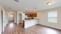 Located at 9872 Trout Tides Blvd in Jacksonville, FL, this two-story home offers five bedrooms and three bathrooms across two well-proportioned floors. The main level features an open-concept kitchen and living area anchored by a granite-topped island with a built-in sink, warm wood cabinetry, stainless steel appliances, and recessed lighting. A walk-in pantry adds practical storage, and wood-look flooring flows seamlessly throughout. A sliding glass door in the living area fills the space with natural light and provides views of the outdoors. A central hallway connects the main-level rooms, with a staircase leading to the upper floor, which houses the majority of the bedrooms including a spacious primary suite. The bedrooms are bright and well-sized, each featuring wood-look flooring and window blinds for privacy. The three bathrooms are finished consistently with granite-topped vanities and rich wood cabinetry. Two bathrooms feature tub-shower combos, while a third offers a tiled walk-in shower with a built-in niche. The attached garage provides convenient enclosed parking and additional storage space. Neutral tones and clean finishes give the home a cohesive, move-in-ready aesthetic throughout.