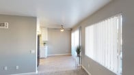 Located at 5544 Balboa Arms #D1 in San Diego, this single-story unit offers a straightforward, well-maintained layout with a neutral color palette throughout. The open living area is bathed in natural light from a large window dressed with vertical blinds, creating a bright and airy atmosphere. Light wood-look flooring extends through the main living and kitchen spaces, while plush carpeting covers the bedroom areas, adding warmth underfoot.

The kitchen is efficiently arranged in a galley configuration, featuring white cabinetry, light stone-look countertops, a double stainless steel sink, and stainless steel appliances including a refrigerator and range. Ample upper and lower cabinet storage keeps the space organized and functional.

The living area transitions smoothly into the carpeted bedroom spaces, each offering neutral gray walls, natural light from windows with vertical blinds, and generous room to accommodate furnishings. A ceiling fan in the main living area provides additional climate comfort.

The bathroom is finished in a clean, all-white palette, complete with a vanity featuring a mirrored medicine cabinet, lighted fixture, and wood-look tile flooring. The overall ambiance of the unit is clean, bright, and move-in ready.