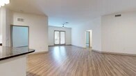 Located at 555 Promenade Pkwy in Irving, Texas, this single-story residence offers a well-organized layout with three bedrooms, three bathrooms, two closets, and a connecting hallway. The open living area is a central highlight, featuring light wood-look plank flooring, crisp white walls, and a ceiling fan overhead. French doors at the far end of the living space invite natural light and provide direct outdoor access, enhancing the bright, airy atmosphere. The kitchen is thoughtfully designed with warm wood-toned cabinetry, dark granite countertops on the island, a white tile backsplash, and a full suite of stainless steel appliances, including a side-by-side refrigerator, range, and microwave. The bedrooms are carpeted for comfort, each featuring windows with blinds that allow natural light while maintaining privacy. The primary bedroom includes access to a walk-in closet with built-in shelving and hanging rods. The bathrooms are finished with wood-grain vanity cabinetry, granite countertops, framed mirrors, and wood-look flooring, presenting a cohesive and modern aesthetic throughout the home.
