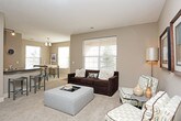 This thoughtfully designed single-floor residence offers a comfortable and functional layout across a generous footprint. The living room serves as the heart of the home, featuring plush carpeting, a large window fitted with horizontal blinds that allows abundant natural light, and neutral taupe walls that create a warm, inviting ambiance. Framed wall art and a textured ceiling add character to the space.

The dining area accommodates a high-top table with bench seating, flanked by two windows overlooking the outdoors, making it an ideal spot for casual meals. The kitchen is outfitted with light maple cabinetry, dark granite-style countertops, hardwood flooring, and black appliances including a range and built-in microwave, offering both style and practicality.

The primary bedroom is a serene retreat with soft carpeting, a ceiling fan, and direct access to a spacious walk-in closet featuring built-in shelving and hanging rods. Its en-suite bathroom includes a glass-enclosed shower, a vanity with dark countertops, and tile flooring. A second bedroom also features carpeting and warm lighting, with an adjacent full bathroom complete with a tub-shower combination, tile surround, and matching dark-countered vanity.