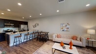 This well-appointed single-story, 3-bedroom, 2-bathroom home offers a thoughtfully designed layout with modern finishes throughout. The open-concept living and dining area is anchored by recessed lighting, wood-style flooring, and neutral tones that create a bright, welcoming atmosphere. A glass door provides direct outdoor access, allowing natural light to fill the space.

The kitchen features dark espresso cabinetry extending to the ceiling, granite countertops, stainless steel appliances including a French door refrigerator, and a breakfast bar that connects seamlessly to the living and dining areas—ideal for entertaining.

Each bedroom is comfortably sized with soft neutral walls and wood-style flooring. One bedroom functions well as a home office, complete with a natural light-providing window. Both bathrooms are finished with dark cabinetry, granite vanity tops, large mirrors, and tub-shower combinations with clean white surrounds.

A dedicated laundry room houses full-size washer and dryer units beneath dark overhead cabinetry for added storage. The hallway connecting the bedrooms is clean and functional, reinforcing the home's cohesive, modern aesthetic throughout.