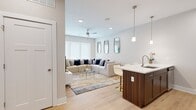This thoughtfully laid-out 1-bedroom, 1-bathroom unit offers a cohesive modern design across its single floor. The open-concept kitchen and living area serves as the heart of the unit, where light hardwood flooring and neutral walls create a clean, contemporary atmosphere. The kitchen is outfitted with rich, dark wood cabinetry, a white quartz peninsula with an undermount sink and bar seating, stainless steel appliances including a refrigerator, electric range, and microwave, plus a subway tile backsplash and stylish pendant lighting overhead. The living room offers a comfortable, well-proportioned space anchored by recessed lighting, a ceiling fan, and a large window that invites natural light. The bedroom is a quiet retreat featuring a sizable window, light hardwood flooring, and ample room for a queen-sized bed. A dedicated closet provides convenient storage. The bathroom maintains the unit's consistent design language with dark wood cabinetry, a white quartz vanity top, a large mirror, and a shower-tub combination. Consistent hardwood-style flooring flows throughout, tying every room together in a unified, modern aesthetic.