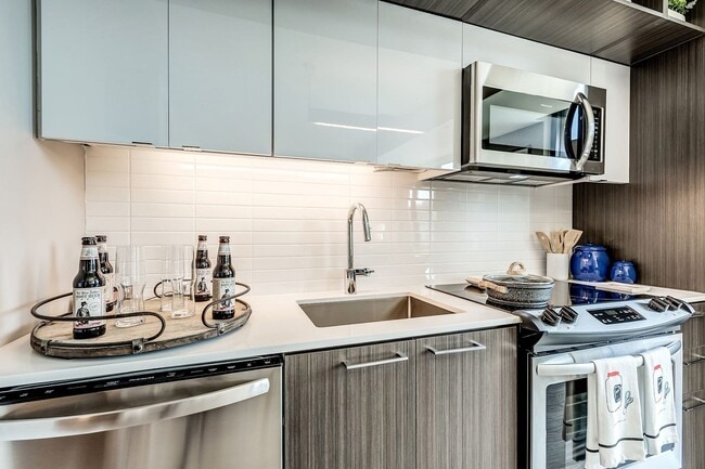 Contemporary kitchens include glass tile backsplash, premium quartz countertops, and designer lighting - Signature Reston Town Center Apartments