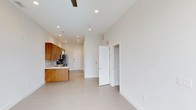 Located at 2304 Hillsborough St in Raleigh, NC, this modern single-floor unit offers a thoughtfully designed open-concept layout that seamlessly connects the living and kitchen areas. The space is finished with large-format, light-toned tile flooring that extends throughout, lending a cohesive and clean aesthetic.

The kitchen is a standout feature, showcasing rich warm-toned wood cabinetry that provides a striking contrast against the bright white walls and light countertops. A stainless steel refrigerator, integrated sink, and a stylish pendant light add both function and character to the culinary space. A tile backsplash completes the kitchen's polished look.

Recessed lighting is installed across the ceiling, providing consistent, well-distributed illumination throughout the open living area. A ceiling fan adds practical comfort to the space. The crisp white walls and clean-lined doors contribute to the unit's contemporary and minimalist character.

The layout includes additional doorways leading to separate rooms, offering a well-defined sense of separation between living and private spaces. The overall ambiance is bright, modern, and move-in ready, reflecting a design sensibility suited for urban living in one of Raleigh's well-connected neighborhoods along Hillsborough Street.