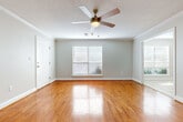 This single-story home offers three bedrooms and two bathrooms across a thoughtfully designed floor plan. The main living area makes a strong first impression with gleaming hardwood floors, crown molding, a textured ceiling, and a ceiling fan with light fixture. Multiple windows dressed with blinds allow natural light to fill the space.

The kitchen is outfitted with white cabinetry, granite-style countertops, and black appliances including a range, over-the-range microwave, and refrigerator. Light tile flooring runs through the kitchen and extends into a bright dining area, which features a large window overlooking greenery outside.

The bedrooms are carpeted and each include ceiling fans and windows with blinds. One bedroom features a closet and connects conveniently to the rest of the home via hardwood-floored hallways. A dedicated laundry room includes tile flooring, overhead shelving, and washer/dryer hookups.

The bathrooms are finished with tile flooring, white vanities with granite-style countertops, and tub/shower combinations. Neutral gray tones throughout the home create a clean, cohesive aesthetic well-suited for a variety of furnishing styles.
