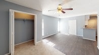 This single-floor studio is thoughtfully designed to maximize its compact footprint, offering an open and efficient layout. The main living area features a combination of wood-style hard flooring and carpet, clearly delineating distinct zones within the open plan. Neutral gray walls throughout create a cohesive, calm atmosphere, while ceiling fans with integrated lighting provide both comfort and illumination. Natural light filters in through windows, brightening the space noticeably.

The kitchen is well-appointed with white cabinetry, granite-style countertops, and black appliances including a refrigerator, range, and dishwasher. Dark hardwood-style flooring runs through this area, adding visual contrast to the white cabinetry. A textured ceiling adds subtle architectural character throughout.

The living zone transitions between hard flooring and carpet, offering flexibility for furniture arrangement. A generously sized closet provides practical storage. The bathroom includes a full tub-shower combination with white tile surround, a granite-topped vanity with an undermount sink, and dark hardwood-style flooring that ties into the rest of the unit's design aesthetic.