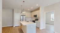 Located at 1090 Summersweet Drive in New Bern, NC, this single-story, 3-bedroom, 2-bathroom home offers a well-designed layout with a clean, modern aesthetic. Light wood-style flooring runs throughout, complemented by neutral beige and white walls that create a bright, cohesive atmosphere.

The open-concept living area features a ceiling fan with light fixture and a glass-paned door that invites natural light and outdoor views. The kitchen is outfitted with white cabinetry, a center island with a light countertop, and stainless steel appliances, making it both functional and stylish.

The generously sized primary bedroom includes a walk-in closet equipped with wire shelving for ample storage, and connects to a well-appointed en-suite bathroom. This bathroom features a double-sink vanity with white cabinetry, a walk-in glass-enclosed shower, and a high transom window for additional natural light.

The two additional bedrooms each include ceiling fans, light wood-style flooring, and windows with horizontal blinds that offer views of the surrounding greenery. A second bathroom provides a tub-shower combination with white subway-style tile surround and chrome fixtures.

Two hallways connect the spaces efficiently, and a dedicated closet adds further storage utility. The home presents a move-in ready, fresh interior throughout.