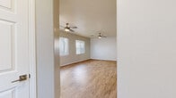 Located in North Las Vegas, Nevada, this two-story home offers 3 bedrooms, 3 bathrooms, and a well-organized layout spread across two floors. The ground floor hosts the main living areas, including an open kitchen and living room, an entrance, and staircase access. The kitchen is outfitted with crisp white shaker cabinets, granite-style countertops, a subway tile backsplash, and a full suite of stainless steel appliances including a gas range, dishwasher, microwave, and refrigerator. Light wood-style flooring runs throughout the main level, complementing the neutral color palette. The living room is bright and airy, featuring dual ceiling fans and multiple windows with blinds that invite generous natural light. A sliding glass door provides outdoor access. The upper floor contains all three bedrooms, three full bathrooms, a hallway, and three closets. The primary bedroom is generously sized and includes a walk-in closet with wire shelving. Additional bedrooms are carpeted, each with a ceiling fan and standard closet. The bathrooms feature wood-style flooring, white cabinetry, granite-style countertops, and tub-shower combinations with tile surrounds. The primary bath includes a dual-sink vanity. Throughout, the home maintains a clean, neutral aesthetic suited for comfortable everyday living.