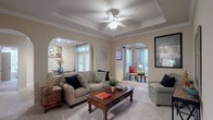 This single-floor residence showcases thoughtful architectural details throughout its well-designed layout. The living room serves as the centerpiece, featuring a coffered tray ceiling with crown molding, a ceiling fan, and soft neutral walls. Two elegant arched doorways frame the space, one leading to the dining area and another to a sitting room, creating a seamless flow between areas. Plush carpeting adds warmth underfoot.

The dining area is bathed in natural light from a set of glass-paned doors that open to the outdoors, enhanced by crown molding and chair rail detailing. The kitchen offers a practical galley-style layout with white cabinetry, under-cabinet lighting, tile countertops, and durable hardwood-style flooring.

The entry foyer welcomes residents with tile flooring and a built-in display ledge. Multiple bedrooms feature carpeted floors, natural light from multiple windows, and neutral walls adaptable to various styles. The bathroom includes a full soaking tub with white tile surround. Throughout, warm beige tones, crown molding, and consistent finishes create a cohesive, comfortable ambiance.
