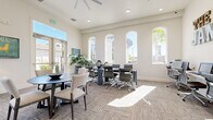 Located at 6201 W Oaks Blvd in Rocklin, California, The James is a thoughtfully designed single-floor office space that blends contemporary style with functional versatility. The space is immediately distinguished by its soaring ceilings and a striking row of tall, arched windows that flood the interior with abundant natural light, casting warm sunbeams across the patterned carpet flooring throughout the day.

The office is organized into several distinct functional zones. A central conference area features a long dark table with modern ergonomic chairs, ideal for team meetings or collaborative work sessions. Adjacent to this is a more casual lounge-style seating area with a round dark table and upholstered chairs, creating an inviting setting for informal discussions or one-on-one meetings. A wall-mounted flat-screen television, a compact media console, and a cozy bench seating nook further enhance this corner of the space.

Along one wall, a dedicated workstation area offers multiple computer terminals with rolling chairs, providing individual workspace beneath a bold marquee-letter sign reading "THE JAMES." Large glass entry doors allow views to the exterior and contribute to the open, airy feel of the office.

Lush potted plants add natural warmth, while recessed lighting and a ceiling fan ensure year-round comfort. The neutral, cream-toned walls and modern furnishings combine to create a professional yet welcoming atmosphere well-suited for leasing, administrative, or collaborative office use.
