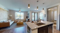 This thoughtfully designed single-floor residence offers a seamless open-concept layout that connects the kitchen, living, and dining areas into one cohesive, light-filled space. The kitchen is a standout feature, showcasing dark cabinetry, stainless steel appliances, granite countertops, and a center island with bar seating illuminated by stylish gold pendant lights. Hardwood-style flooring runs throughout the main living areas, adding warmth and continuity to the space. The living room is generously proportioned, featuring large windows that flood the room with natural light and a ceiling fan overhead. A dedicated dining nook, positioned beside a window with outdoor views, provides an intimate setting for meals. The bedroom is a comfortable retreat, complete with a ceiling fan, access to a private door with natural light, and neutral tones that create a calm atmosphere. The full bathroom features granite countertops with an undermount sink, dark cabinetry, a large framed mirror, and a shower-tub combination with clean tile surround. Throughout the residence, the design balances modern finishes with a warm, inviting ambiance, making it a functional and attractive living space.