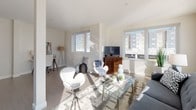 Located at 600 North Beach on Atlantic Avenue in Atlantic City, NJ, this contemporary single-floor residence offers a bright, open-concept layout designed for modern living. The spacious living area is anchored by large windows that flood the space with natural light, showcasing light-toned hardwood-style flooring and clean white walls that enhance the airy atmosphere. A dedicated workspace nook flows seamlessly into the living room, which features ample room for both lounging and entertaining. The kitchen is outfitted with dark wood cabinetry, light quartz countertops, stainless steel appliances, and a stylish mosaic tile backsplash, complemented by a central island with counter seating. The two bedrooms are carpeted for comfort, each offering generous closet space and windows with urban views. One bedroom includes a double-door closet and direct access to a well-appointed bathroom. The bathroom features warm wood-toned cabinetry, a framed mirror, tile flooring, and a clean, modern vanity. Throughout the residence, the design palette remains consistently neutral and contemporary, creating a cohesive and inviting environment that is both functional and refined.