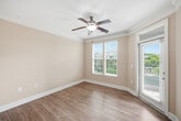 This well-appointed 610-square-foot, one-bedroom, one-bathroom residence at 4000 Penuche Way in Holly Springs, NC offers an efficient and comfortable single-floor layout. Warm wood-style flooring flows consistently throughout the unit, complemented by neutral beige walls, crisp white trim, and crown molding details that lend a polished finish to the space.

The open-concept living room is bright and inviting, featuring large windows with blinds, a ceiling fan with light fixture, and a glass-paneled entry door that invites abundant natural light and outdoor views. The kitchen is separated by a raised breakfast bar with granite countertops and pendant lighting overhead. It includes cream-toned cabinetry, stainless steel appliances—including a side-by-side refrigerator and range—and ample storage.

The 150-square-foot bedroom is a comfortable retreat with its own ceiling fan, natural light from a window, and direct access to adjacent spaces. The full bathroom features a tub/shower combo, a cream vanity with brushed nickel hardware, and wood-style flooring. A dedicated laundry area houses a stacked washer and dryer, adding everyday convenience. A hallway and closet complete this thoughtfully designed home.