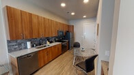 Located at 1001 W Rosedale St in Fort Worth, Texas, this single-floor unit offers a contemporary and functional design throughout. The open-concept layout seamlessly connects the kitchen, dining, and living areas, creating a cohesive and efficient use of space.

The kitchen is a standout feature, outfitted with warm-toned wood cabinetry extending floor to ceiling, granite-style countertops, and a slate tile backsplash that adds texture and depth. Stainless steel appliances — including a refrigerator, electric range, built-in microwave, and dishwasher — complete the well-equipped cooking space. A compact dining area with a glass-top table sits adjacent to the kitchen near the entryway.

The living room receives generous natural light through large vertical-blind-covered windows and features light wood-look flooring that carries throughout the unit. A wall-mounted television and thoughtfully arranged seating make it a comfortable gathering space.

The bedroom is a calm, neutral retreat with dual windows offering outdoor views and a ceiling fan for added comfort. Clean white walls and ample natural light give the room an airy feel.

The bathroom includes a granite-topped vanity with wood cabinetry, a shower with tiled surround, and direct access to a dedicated walk-in closet with built-in rod storage, providing practical organization.