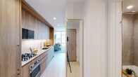 Located at 354 N Union Ave in Chicago's Fulton River District, this single-floor unit showcases a contemporary design with a cohesive warm-toned aesthetic throughout. Light wood finishes, recessed lighting, and light-toned flooring create a bright, airy atmosphere from entry to living space.

The galley-style kitchen is well-equipped with stainless steel appliances, including a gas cooktop, wall oven, and built-in microwave. Granite countertops complement the light wood cabinetry that extends floor to ceiling, maximizing storage. A full-length gold-framed mirror near the entry enhances the sense of space.

The living area is defined by dramatic floor-to-ceiling windows and sliding glass doors that open to a balcony, offering expansive views of the Chicago skyline. Natural light floods the space, creating a striking connection between the interior and the city beyond.

The bedroom features textured accent wall coverings and large windows that continue the city view experience. Two bathrooms serve the unit—one with a glass-enclosed walk-in shower, wood vanity, and open shelving, and a second full bath with a shower-tub combination, both finished with large-format tile flooring and warm wood cabinetry.