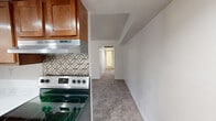 This single-floor residence offers three bedrooms and one bathroom within a thoughtfully arranged layout. The kitchen serves as a functional centerpiece, featuring warm medium-toned wood cabinetry extending to the ceiling, light marble-style countertops, stainless steel appliances including a dishwasher and refrigerator, a double-basin sink, and a decorative patterned tile backsplash. Hardwood-style flooring runs throughout the kitchen, while a small chandelier adds a touch of character to the adjacent dining area.

The living area is carpeted and benefits from natural light through a sliding glass door that opens to the outdoors. Each bedroom is finished with plush carpet, neutral white walls, and standard closets equipped with hanging rods and overhead shelving. The primary bedroom offers a comfortable footprint, and secondary bedrooms include windows that bring in natural light.

A central hallway connects the rooms, maintaining an efficient flow throughout the unit. The bathroom is finished with a white vanity, solid-surface countertop, a mirrored medicine cabinet with integrated lighting, and chrome fixtures, presenting a clean and functional design.