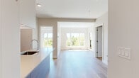 This well-appointed 2-bedroom, 2-bathroom unit is thoughtfully designed on a single floor, offering a bright and modern living experience. The open-concept layout connects the kitchen and living room seamlessly, all finished with light hardwood flooring that runs throughout the space.

The kitchen is a standout feature, equipped with stainless steel appliances including a refrigerator, electric range, and microwave. A large island with a quartz countertop and undermount sink serves as both a workspace and casual gathering spot. Cabinetry combines white upper cabinets with warm wood-toned lower units, striking a clean, contemporary balance.

The living area is bathed in natural light through large windows that frame lush treetop views, creating an airy and inviting atmosphere. Both bedrooms continue the light hardwood flooring and feature windows with greenery views; the primary bedroom includes access to a private outdoor balcony.

The two bathrooms are finished with modern fixtures and warm wood-toned vanities. The main bathroom features full-height tiled walls surrounding a soaking tub, while the second bathroom offers a clean, functional design with a mirrored vanity and built-in shelving. A hallway connects all rooms efficiently, completing this well-organized and contemporary layout.