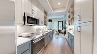 Located at 4604 E Cactus Rd in Phoenix, AZ, this efficiently designed single-floor studio offers a cohesive, modern aesthetic with high-quality finishes throughout. The open-concept kitchen and living area form the heart of the space, where a galley-style kitchen impresses with two-tone cabinetry — soft white upper cabinets paired with slate-blue lower cabinets — complemented by crisp white quartz countertops, a classic subway tile backsplash, and stainless steel appliances including a built-in oven, microwave, and refrigerator. A built-in shelving unit at the kitchen's edge provides additional storage and display space. The living area transitions seamlessly from the kitchen, bathed in natural light from multiple large windows dressed with white blinds and anchored by a bold black entry door. Light hardwood flooring runs continuously throughout, lending warmth and visual continuity. Soft, neutral-toned walls enhance the bright, airy ambiance. The bathroom is finished with large-format grey tile flooring, shaker-style cabinetry in a warm grey tone, a white countertop vanity, globe sconce lighting, and a full tub-shower combination. A dedicated closet rounds out this well-appointed space, making it a functional and stylish residence in the heart of Phoenix.