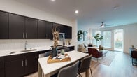Located at 3600 San Pablo Ave in Hercules, California, this single-floor residence offers a thoughtfully designed open-concept layout that seamlessly connects the kitchen, dining, and living areas. The kitchen is a standout feature, showcasing dark espresso cabinetry reaching to the ceiling, white subway tile backsplash, light quartz countertops, and a full suite of stainless steel appliances including a refrigerator, electric range, and microwave. A white dining table with bar-height seating sits adjacent to the kitchen, creating a natural flow into the space. The living area is bright and airy, benefiting from large windows with plantation-style blinds that invite natural light and outdoor views. Light wood-style flooring runs throughout the main living spaces, complementing the neutral color palette. The bedroom is a serene retreat with plush carpeting and access to a walk-in closet equipped with wire shelving and generous hanging space. A full bathroom with dark vanity cabinetry and a clean, minimalist aesthetic serves the bedroom. An additional half bath provides convenience. A dedicated in-unit laundry closet with a stacked washer and dryer adds everyday practicality to this well-appointed residence.