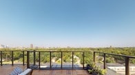 Located in the heart of Dallas, TX, this single-level rooftop terrace at 5619 Belmont Ave offers an exceptional outdoor experience defined by thoughtful design and commanding views. The space is finished with rich, warm-toned hardwood deck tiles laid in a classic herringbone pattern, adding a refined texture underfoot that complements the overall aesthetic.

The terrace features glass-panel railings supported by dark metal and timber posts, ensuring unobstructed sightlines across the Dallas skyline and the lush tree canopy of the surrounding East Dallas neighborhood. On clear days, the panoramic view stretches across a broad expanse of treetops to the distant city skyline — a standout feature of this outdoor space.

The exterior walls are clad in wood shake-style shingle siding in a neutral taupe tone, providing a warm, natural backdrop. Large sliding glass doors and a steel-framed glass entry door provide seamless access to the interior, blurring the boundary between indoor and outdoor living. Planter boxes along the railing add greenery and a welcoming touch.

This rooftop terrace is well-suited for outdoor entertaining or relaxation, offering an elevated vantage point, abundant natural light, and open-sky exposure that captures the vibrant energy of the Dallas urban landscape.