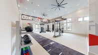 Located in Orlando, FL, this expansive fitness center offers a generously proportioned, single-floor open layout designed to accommodate a wide variety of training styles. Soaring ceilings create an airy, energizing atmosphere, while large multi-pane windows line the walls, flooding the space with abundant natural light and offering views of the surrounding outdoors.

The facility is anchored by a multi-station functional training rig complete with suspension trainers, hanging punching bags, and cable attachments, providing versatile strength and conditioning options. A long turf sprint track runs centrally through the floor, ideal for speed and agility drills. Cardio equipment — including air bikes and rowing machines — is thoughtfully arranged to maximize open floor space.

A dedicated free weights area features organized racks stocked with kettlebells and medicine balls in varying weights, alongside adjustable benches. Additional equipment such as a tire and battle rope rounds out the functional fitness offerings.

Bold, large-scale motivational murals bearing words like "CONFIDENT," "POWER," "COMMITMENT," and "ENDURE" energize the walls, reinforcing an athletic and goal-driven ambiance throughout. Oversized ceiling fans ensure consistent air circulation across the entire space. The bright, white interior palette with light flooring keeps the environment clean, modern, and performance-focused.